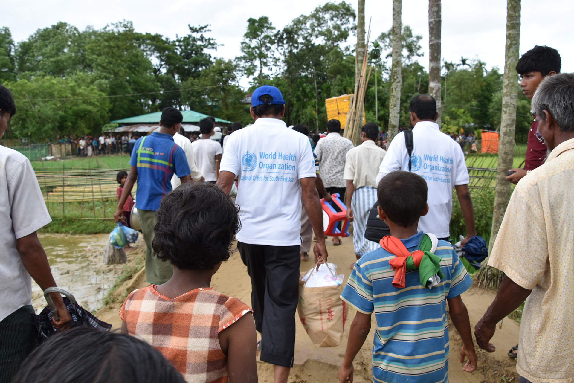a group of people including some children walking with their backs to the camera